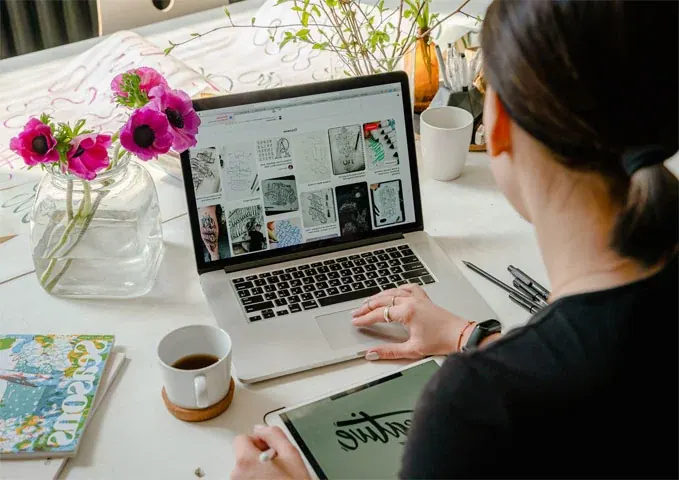 Designer planning a website layout on a laptop with sketches on the desk